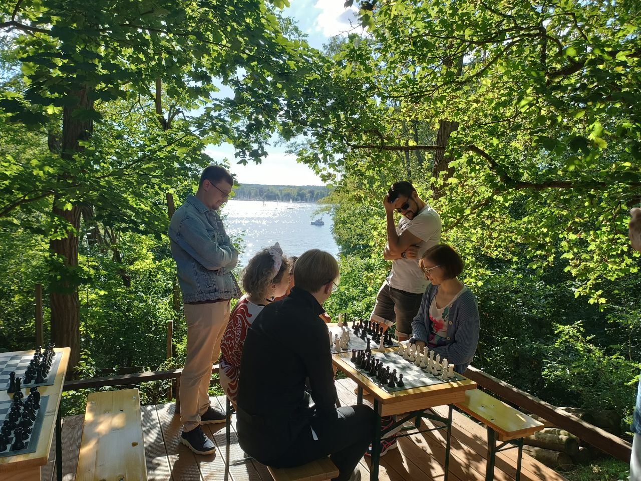 Guests around a chess table with the lake in view